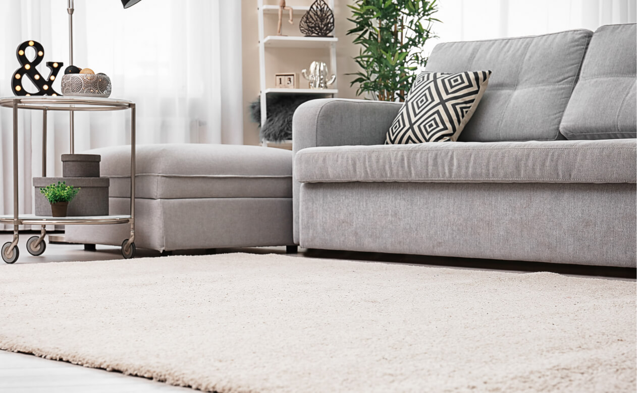 Living room with soft grey and cream furniture and carpet.